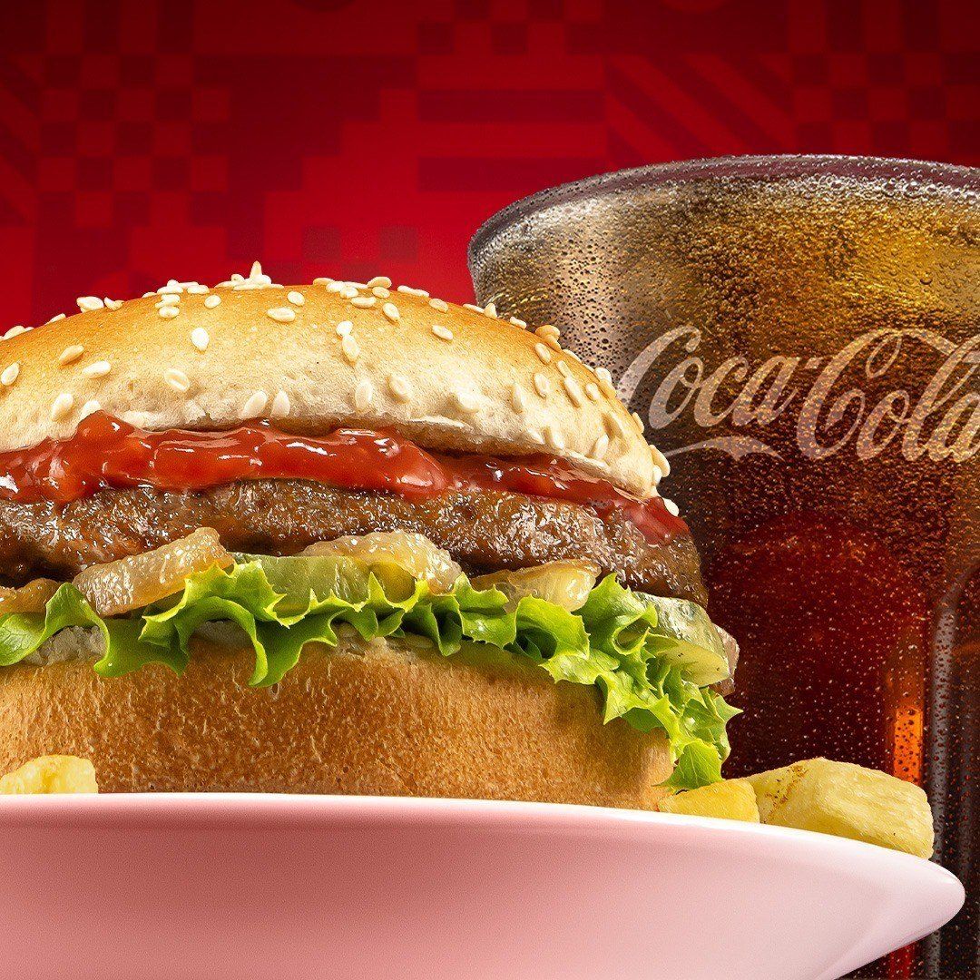 Wimpy beef burger served with a glass of Coca-Cola.