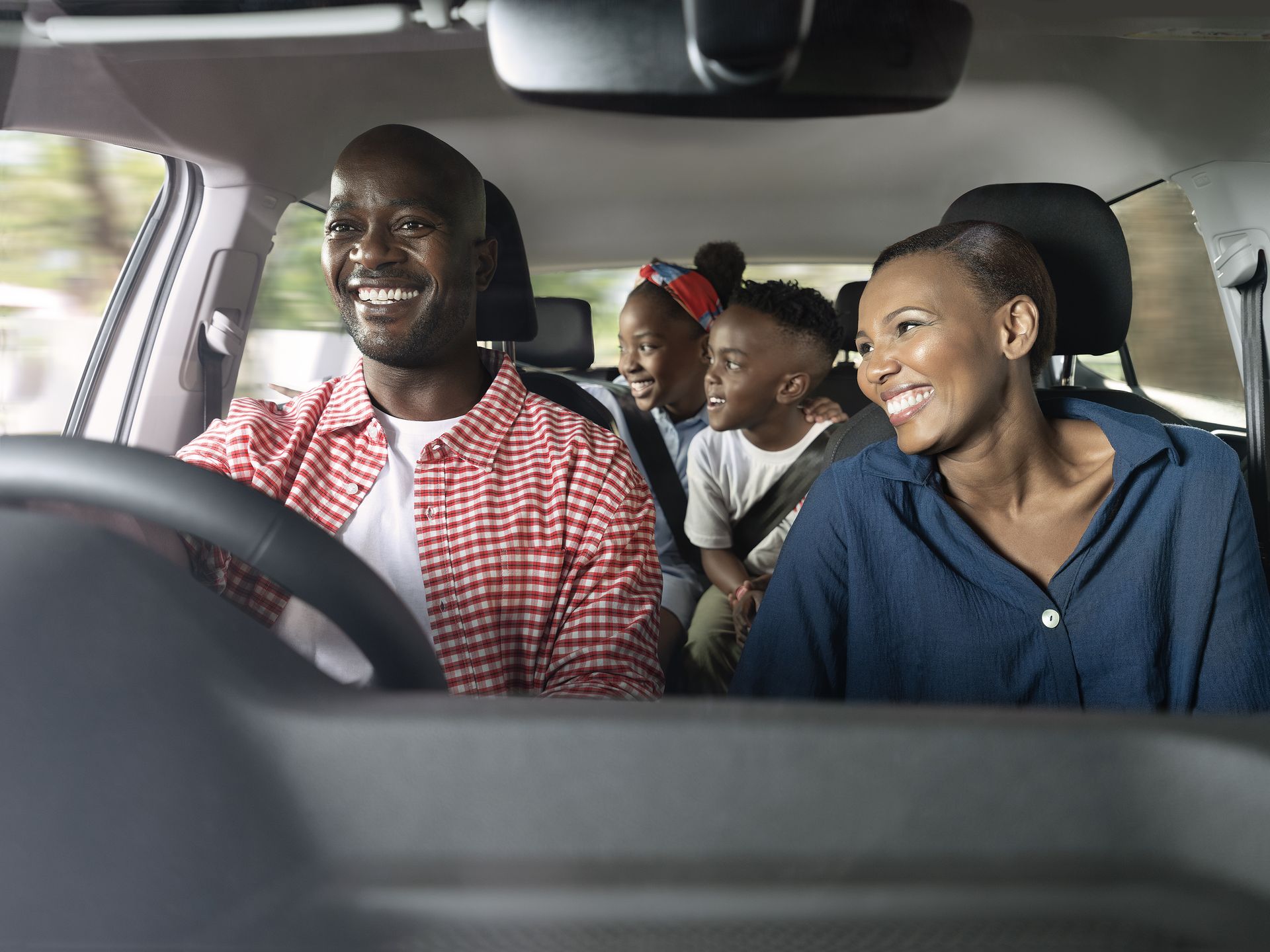 A happy family, a father, mother and 2 children traveling in a vehicle