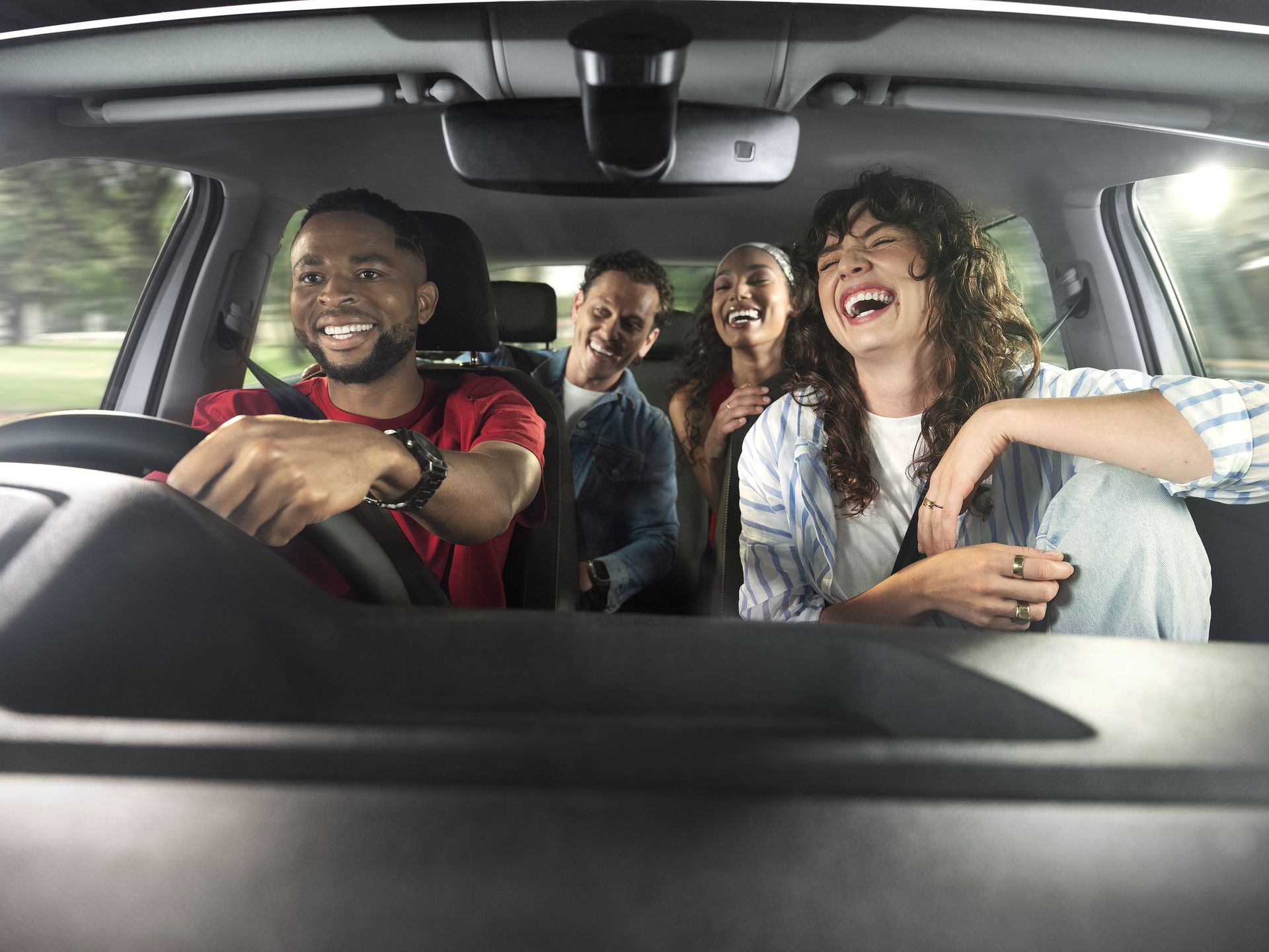four friends laughing and travelling in a vehicle